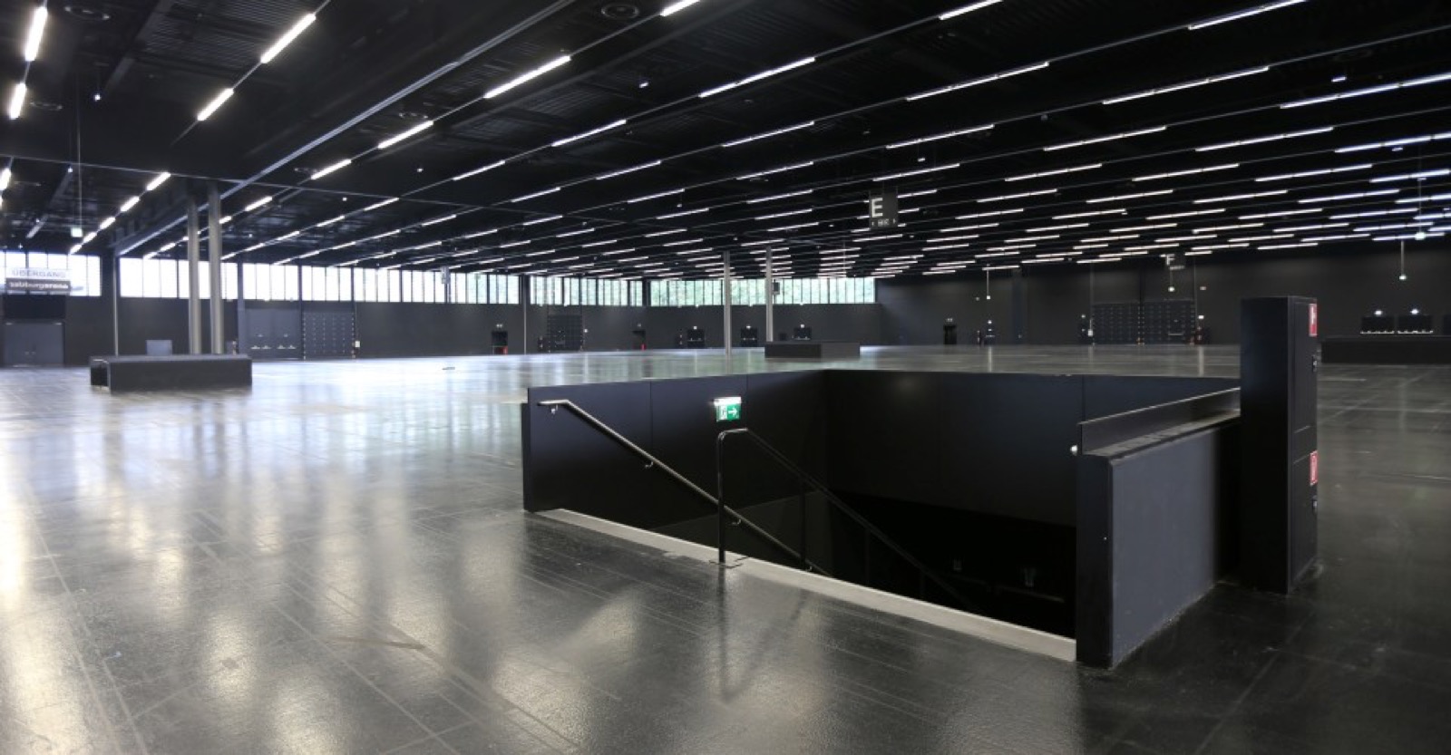 Padiglione fieristico vuoto, pavimento lucido, capriate e luci a soffitto a vista, prima del montaggio degli stand.